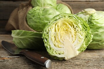 Fresh whole and cut cabbages on wooden table, closeup