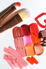 Different cosmetic products and makeup brushes on white background, flat lay
