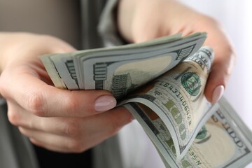 Woman counting dollar banknotes indoors, closeup view