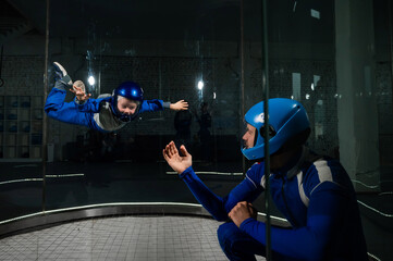 A man teaches a boy to fly in a wind tunnel. Lack of gravity.