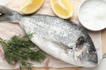 Fresh raw dourade with spices on white wooden table, closeup. Fish and seafood delicacies