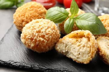 Delicious fried croquette balls with basil on grey table, closeup