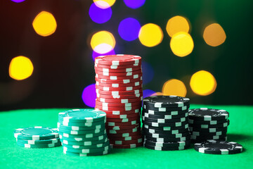 Casino chips on green table against blurred lights, closeup