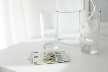 Tips, glasses and jug of water on white counter, closeup