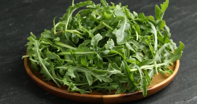 Fresh ripe green arugula leaves on black table, closeup. Camera zooming in