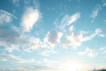 Bright blue sky with scattered fluffy white clouds and the sun shining near the horizon creating a serene and uplifting atmosphere