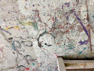 View of the floor of an an arts studio covered in layers of various coloured paint marks on the concrete floor