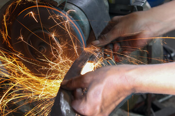 Worker working with hand grinder on metal construction. Electric wheel grinding on steel structure...