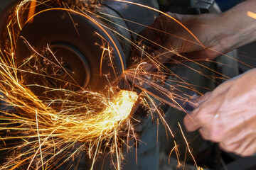 Worker working with hand grinder on metal construction. Electric wheel grinding on steel structure...