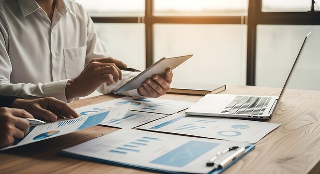 Collaborative business meeting featuring a team reviewing financial charts and a tablet device, Corporate analysis and reporting of data with a team approach to office technology