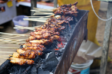 Grilling satay over charcoal embers is an authentic indonesian culinery speaciality. Processed making chicken satay.