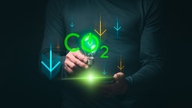 Concept of reducing CO2 emissions for the environment and sustainable development based on renewable energy. Businessman's hand is showing the reduction of CO2 as targeted for green cities by 2050.