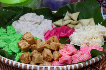 Traditional javanese food (gethuk,cenil,lupis etc) on a tray made of woven bamboo and lined with banana leaves at a traditional market.