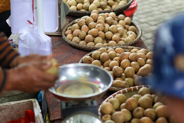 A pile of fresh sapodilla at a traditional market in Balikpapan. buyers are choosing sapodilla...