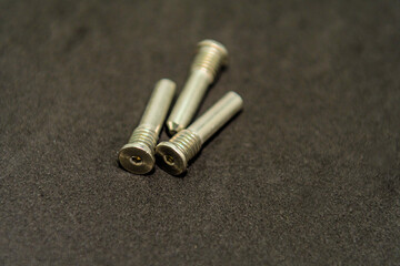 Three arranged metal screws on a dark background surface