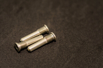 Three metal screws closely arranged on a dark surface