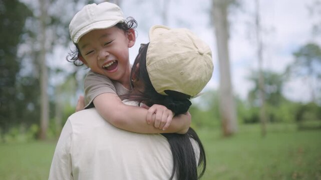 Asian mom and son share a warm hug with laughter. A candid scene of family connection, childhood happiness, and unconditional love.


