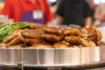 A dish of braised pig trotters (or pork hocks), which are a popular delicacy in many Asian cuisines.The pig trotters appear to be cooked in a rich, savory sauce, involving soy sauce, garlic, and spice