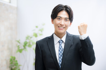 ビジネススーツでガッツポーズをする若い男性　リクルートやプレゼンなどのイメージカメラ目線
