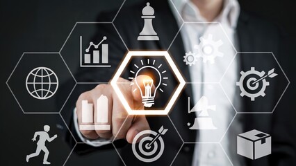 Businessman touching lightbulb on screen with business strategy icons in a hexagonal grid