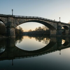 Fototapeta premium Stunning Architectural Reflection of a Historic Bridge Transcending a Peaceful River in Early Morning Light