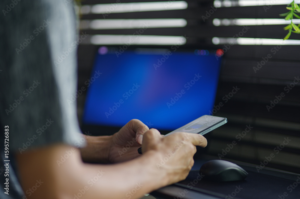 Poster person using smartphone near computer in modern workspace