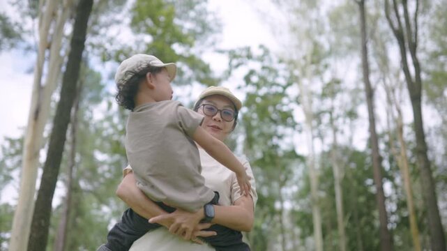 Mother and daughter enjoying quality time outdoors in a green forest, smiling and embracing during a family adventure, capturing love, happiness, companionship, parenting, and childhood.