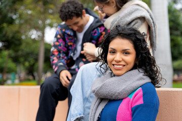 Fototapeta premium Young latin american woman smiling with friends in background