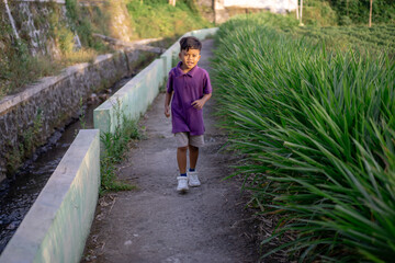 Child jogging alone in nature near the garden park on a very sunny day. High quality photo