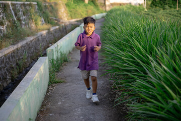 Child jogging alone in nature near the garden park on a very sunny day. High quality photo
