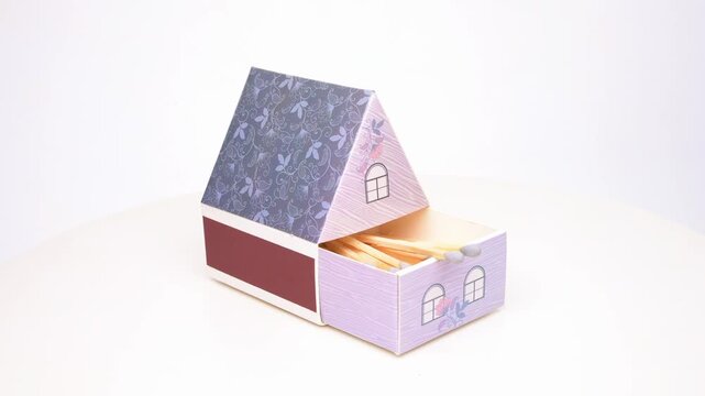 house shape matchbox and match sticks rotating on white at horizontal composition