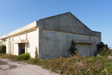 Abandoned concrete warehouse covered in overgrowth