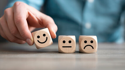 Hand selecting happy wooden dice from neutral and sad faces