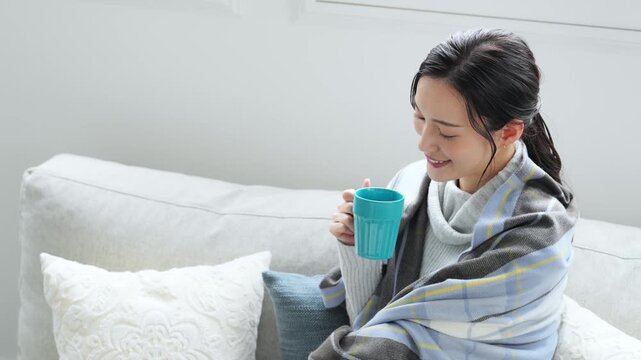 女性、飲む、寒い、冬、暖かい、コーヒー、笑顔、日本人、暖冬、対策、防寒、ストール、ショール、ブランケット、コピースペース、インテリア、リビングルーム、ライフスタイル、おしゃれ、リラックス、ほっこり、安心、ソファー、若い、寒暖差、紅茶、カップ、暖房、エアコン、マフラー、ポジティブ、快適、節電、室内、明るい、省エネ、爽やか、毛布、シンプル、キレイめ、きれいめ、寒さ、寒気、冷気、住宅、俯瞰、ハイアングル