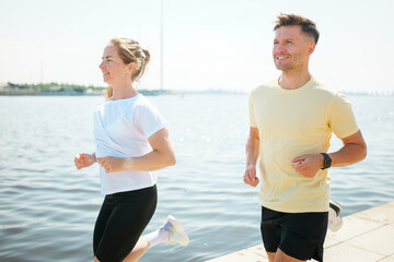 Couple enjoying a sunny jog along the waterfront promenade in summer