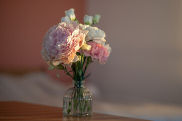 Compact bouquet of peony carnation lisianthus arranged in clear glass vase on table under sunlight. Floral composition of decorated romantic flowers, home interior styling with spring bouquet