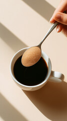 A person adding sugar to their coffee.