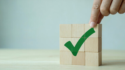Hand placing wooden blocks with a green check mark, symbolizing approval and success