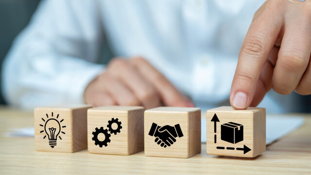 Hand selecting wooden block with supply chain icon, representing business concepts