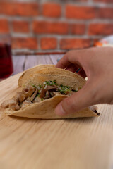 Close-up of a person's hand holding a pork carnitas taco, Mexican food