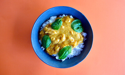 A top view of butter chicken and white rice in a bowl.