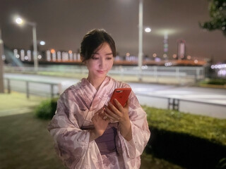 スマートフォンでメッセージを入力する浴衣姿の女性