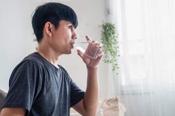 Young Asian Man Drinking Water as Part of a Healthy Routine  Self Care, Wellness, and Daily...