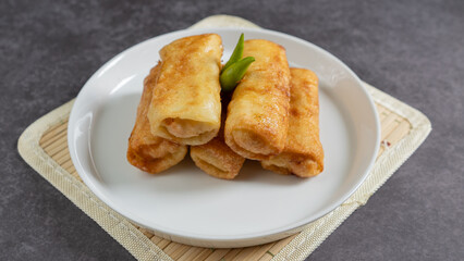 Sosis Solo (Sausage Solo). Special designation for a chicken dish wrapped in an omelet and shape like sausagea. Traditional Indonesian meat snack, served on a white plate with green chili garnish.