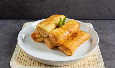 Sosis Solo (Sausage Solo). Special designation for a chicken dish wrapped in an omelet and shape like sausagea. Traditional Indonesian meat snack, served on a white plate with green chili garnish.