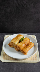 Sosis Solo (Sausage Solo). Special designation for a chicken dish wrapped in an omelet and shape like sausagea. Traditional Indonesian meat snack, served on a white plate with green chili garnish.