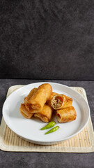 Sosis Solo (Sausage Solo). Special designation for a chicken dish wrapped in an omelet and shape like sausagea. Traditional Indonesian meat snack, served on a white plate with green chili garnish.