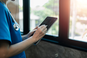 Medical professional in blue scrubs using a tablet with a stylus, emphasizing modern healthcare...