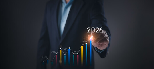 Business professional in suit points to glowing 2026 above upward bar chart from 2021–2025,...