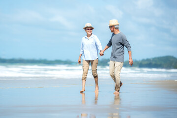 Asian Lifestyle senior couple walking chill on the beach happy in love romantic and relax time after retirement.  People tourism elderly family travel leisure and activity after retirement
